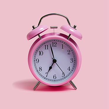 Alarm clock on pink background