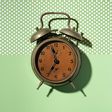 Vintage alarm clock on green background