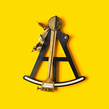 Studio shot of navigational octant against yellow background