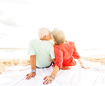 Rear view of couple kissing on beach at sunrise, Jupiter, Florida