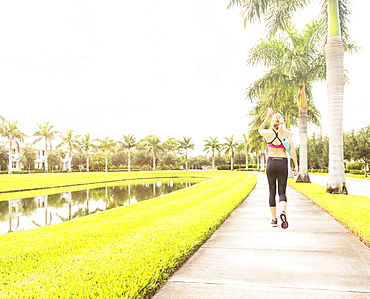 Woman walking along promenade drinking water, Jupiter, Florida