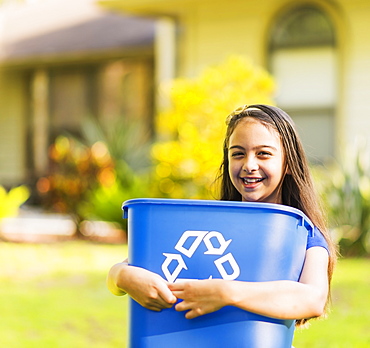 Portrait of girl ( 8-9) holding recycling bin