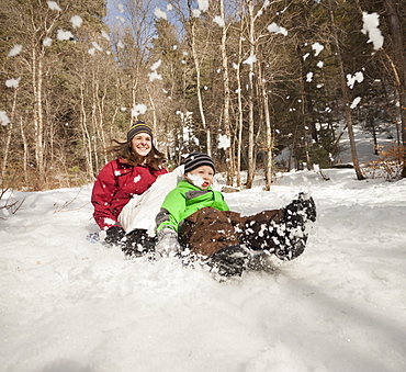 Young woman sledding with boy (4-5), USA, Utah, Highland