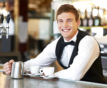 Portrait of barista holding milk jug 