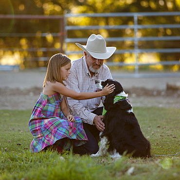 Girl (8-9) stroking dog with grandfather