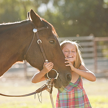 Portrait of smiling cowgirl (8-9) with horse in ranch