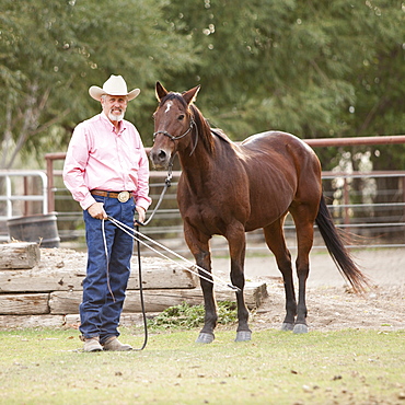 Portrait of senior man with horse in ranch