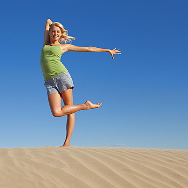 Woman doing dance pose at the beach