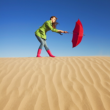 Woman holding red umbrella in the desert