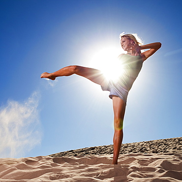 Female dancer kicking her leg on the beach