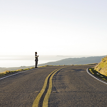 Businessman standing on remote road