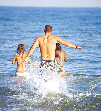 Young friends running into ocean