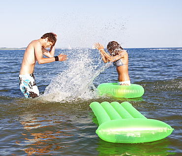 Young couple splashing in ocean