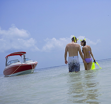 Couple with snorkeling gear walking in water, Florida, United States