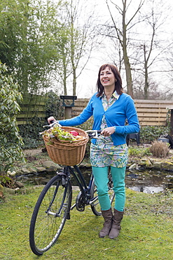 Mature woman with fresh vegetables in bike basket, Venlo, Netherlands