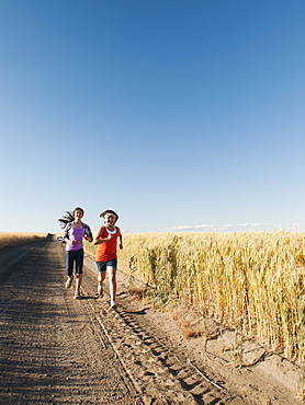 Girls (12-13, 10-11) running along dirt road