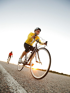 Mid adult couple cycling on empty road