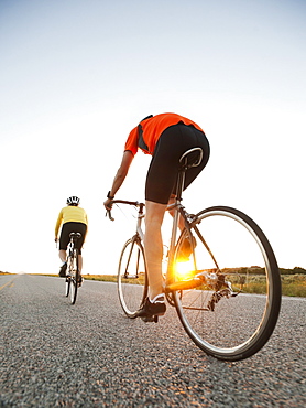 Mid adult couple cycling on empty road