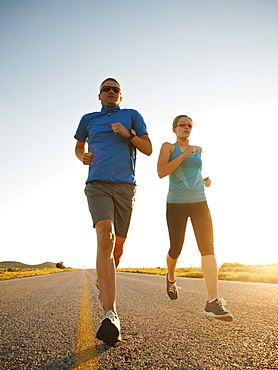 Mid adult couple running on empty road