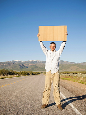 Mid-adult man hitch-hiking in barren scenery