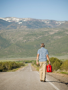 USA, Utah, Kanosh, Mid adult man carrying empty canister along empty road