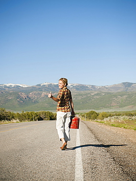 Mid adult woman carrying empty canister attempting to stop vehicles for help