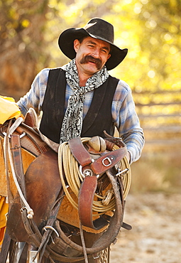 Cowboy holding saddle