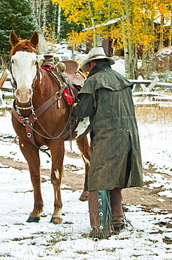 Man putting saddle on horse