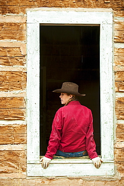 Cowgirl sitting on window ledge