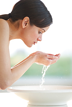 Mid-adult woman washing her face in bowl