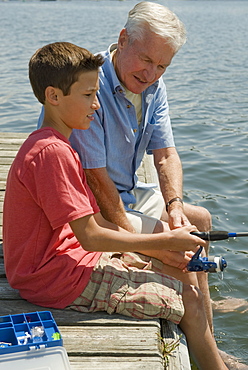 Grandfather and grandson fishing off dock