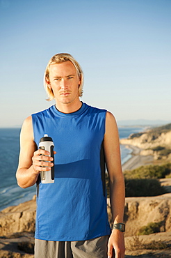 USA, California, San Diego, Portrait of male jogger holding water bottle