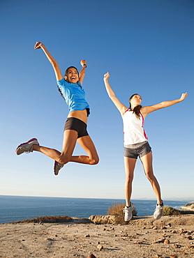 USA, California, San Diego, Two women jumping at sea coast