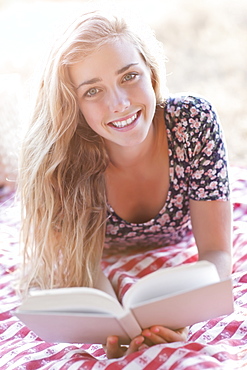 Happy teenage girl (16-17) reading book outdoors