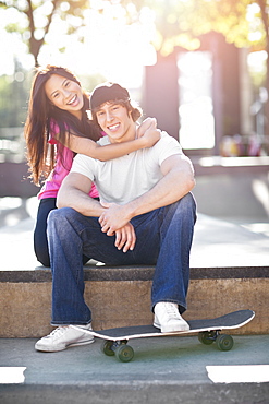 Young multi-racial couple posing with skateboard