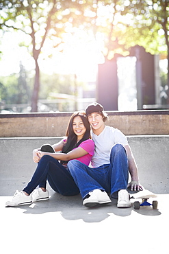 Young multi-racial couple posing with skateboard