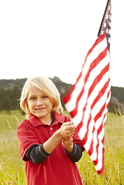 Portrait of boy (6-7) waving American flag