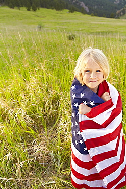 Portrait of boy (6-7) wrapped in American flag