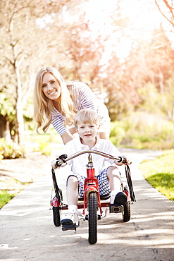 Mother and son (2-3) riding tricycle in park