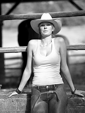 USA, Colorado, Portrait of cowgirl sitting by fence