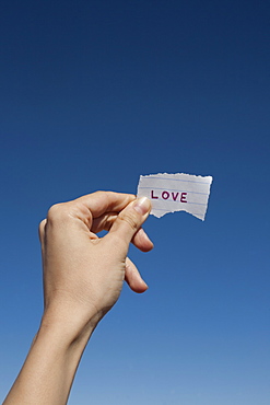 USA, Arizona, Winslow, Human hand holding love note against blue sky