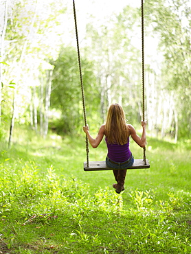 USA, Colorado, Mature woman swinging, rear view