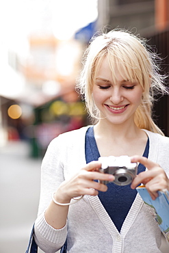 USA, Seattle, Smiling young woman holding digital camera