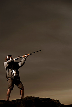 Man aiming rifle on rocks