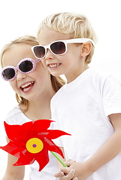 Girl (10-11) and boy (4-5) wearing sunglasses on beach