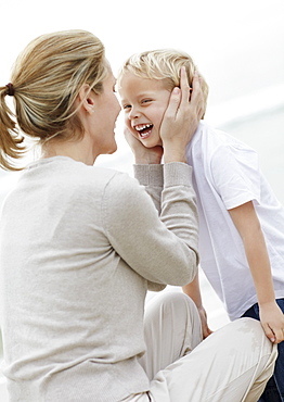 Boy (4-5) playing on beach with mother