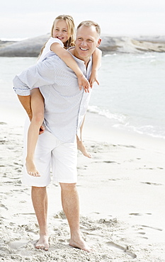 Girl (10-11) playing on beach with father