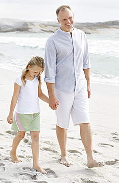 Girl (10-11) playing on beach with father