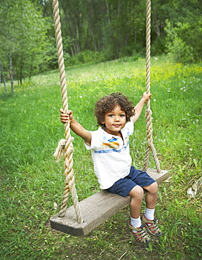 Young child sitting on large outdoor swing