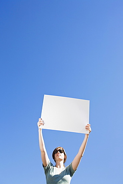 Young woman holding a blank placard